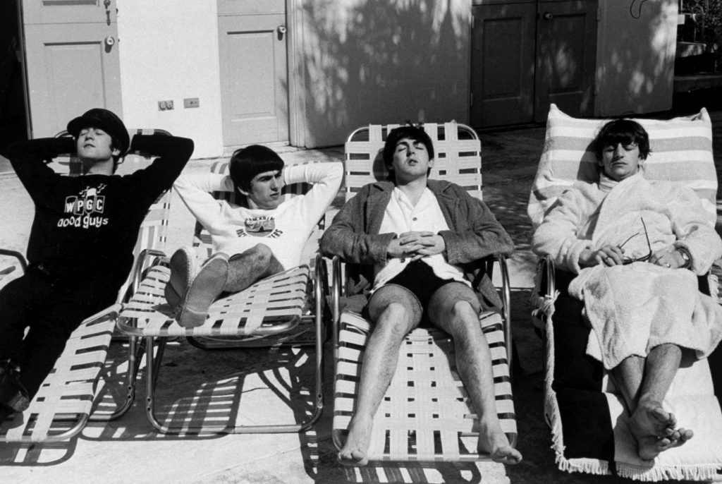 black and white photo of the Beatles lounging in pool chairs in Miami, 1964